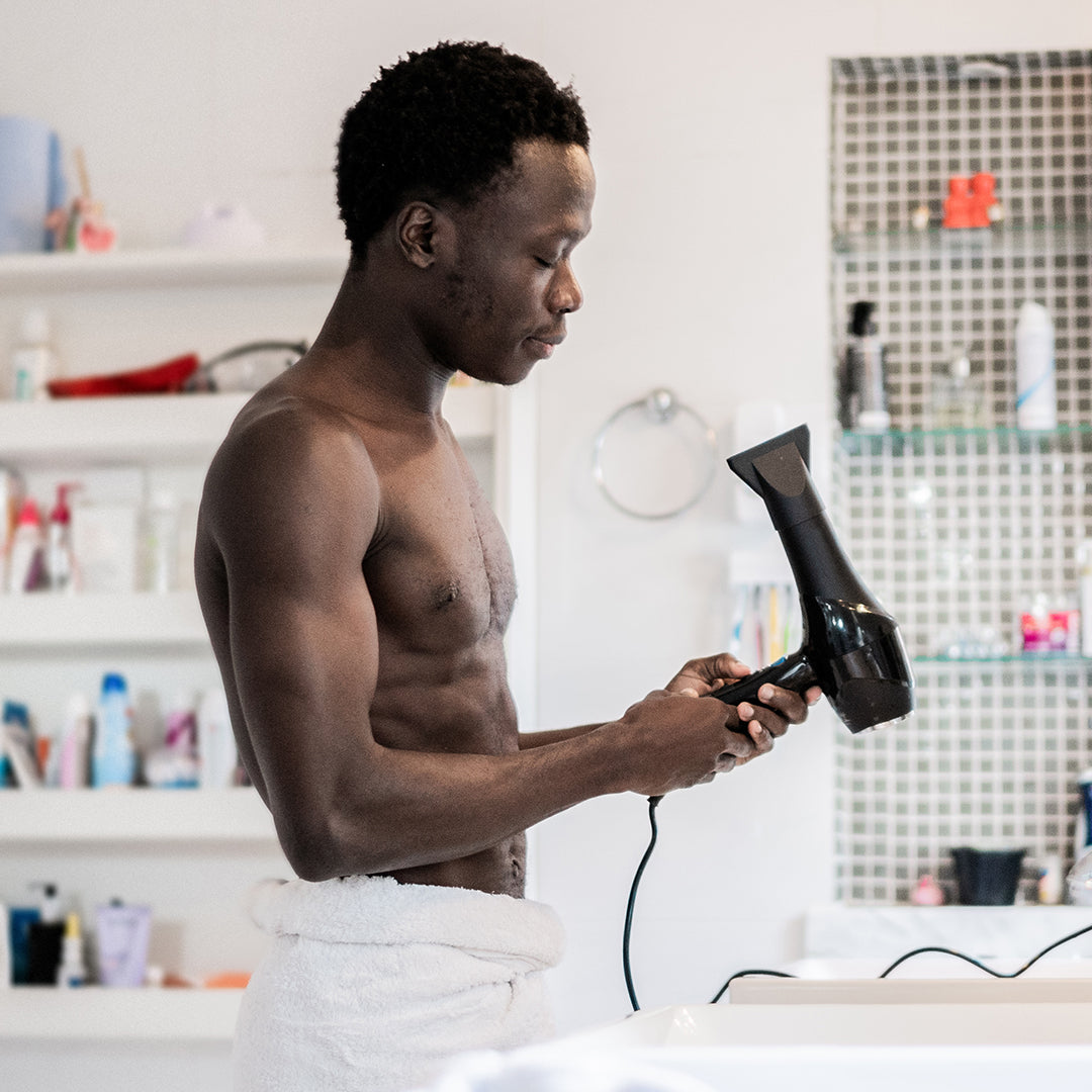 african american young man wearing a towel blow drying afro hair