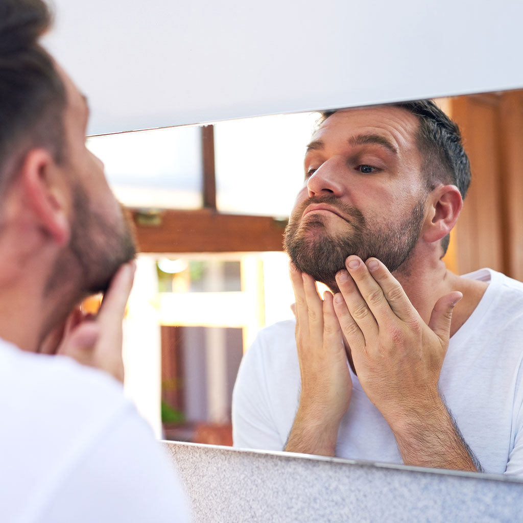 Man Touching Face In Miror