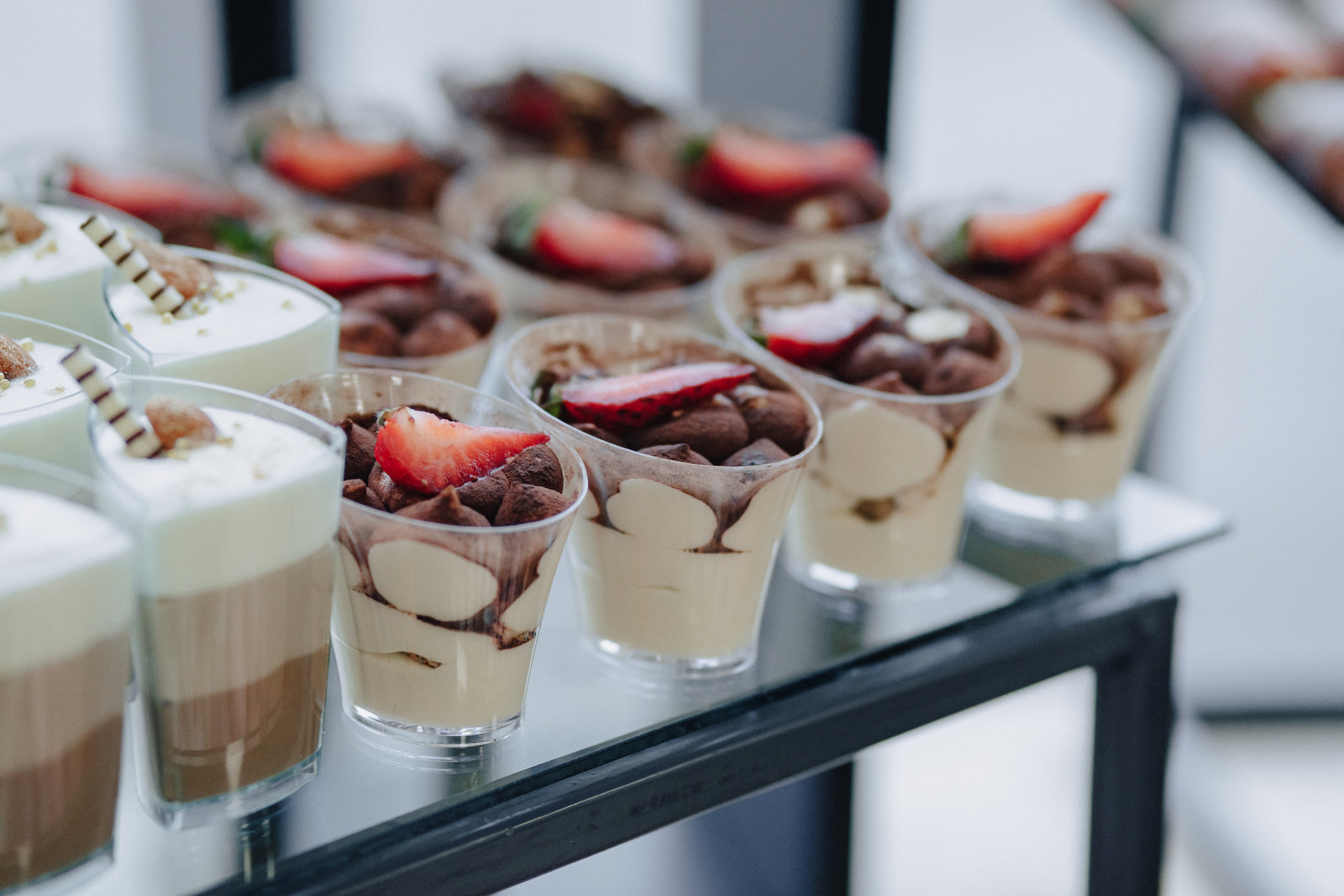 Refined dessert table with mini disposable bowls and cutlery, showcasing an array of elegant desserts