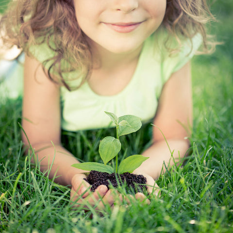 a little girl holding green plant in her hands