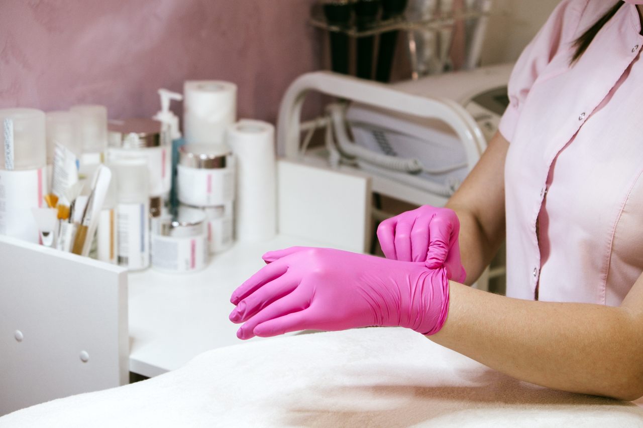 female hand beautician cosmetologist in pink medic