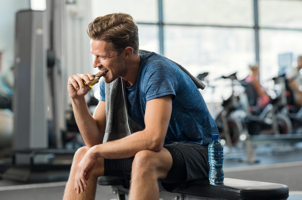 man eating a snack in gym while sitting