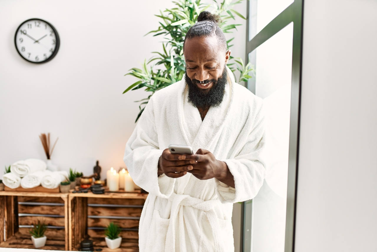 black man with white robe texting by phone