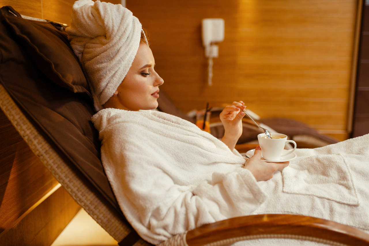 sexy girl relaxing with cup of coffee in spa chair