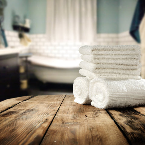 white towels standing on the wooden surface and in front of the bath tube
