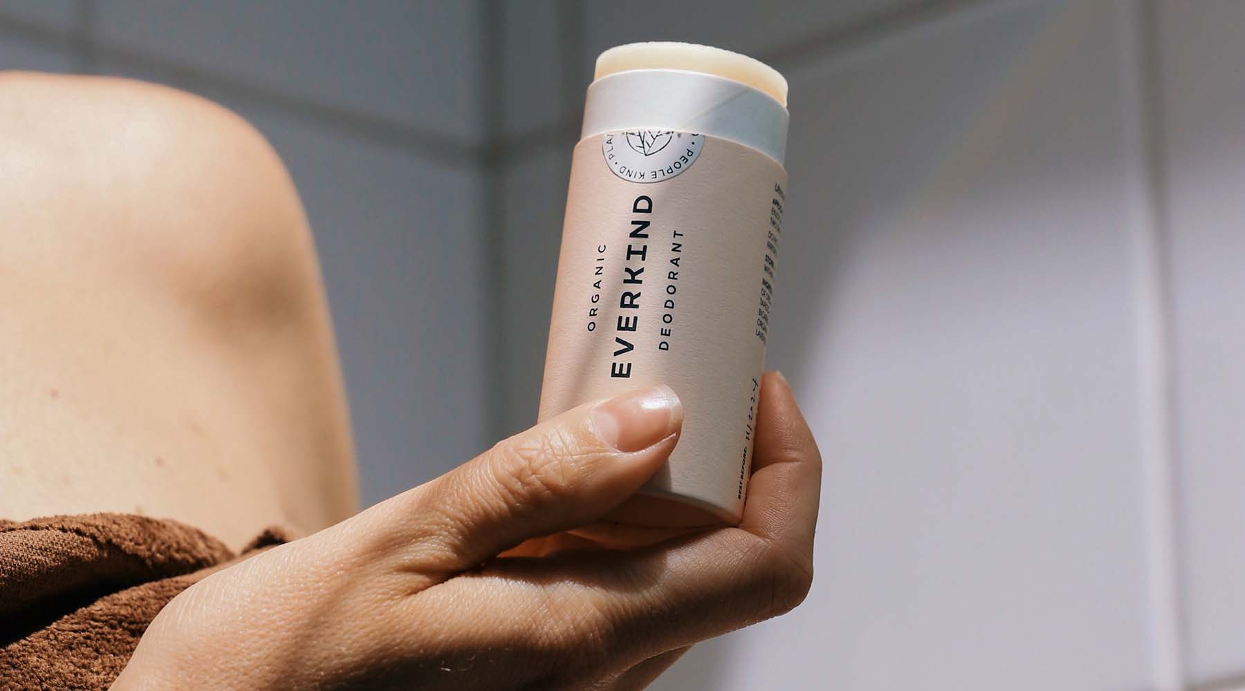 Holding Everkind organic natural deodorant in compostable packaging, ready to apply.