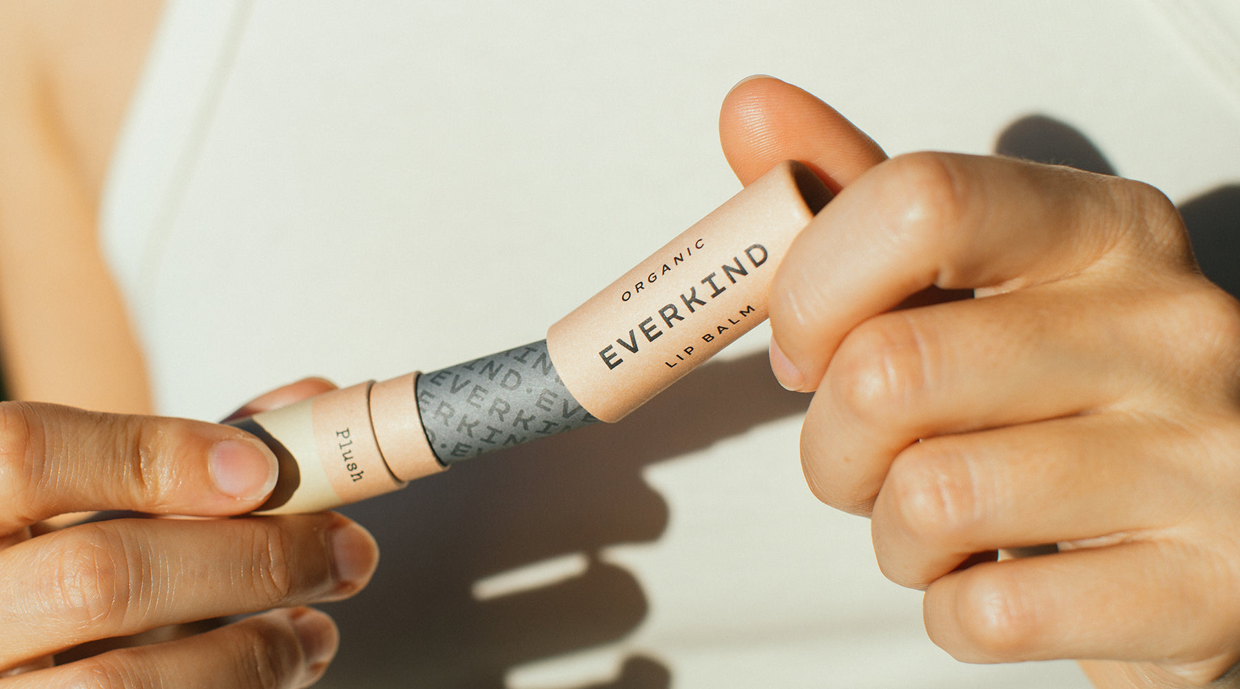 Photo of woman opening Everkind's home compostable lip balm tube.