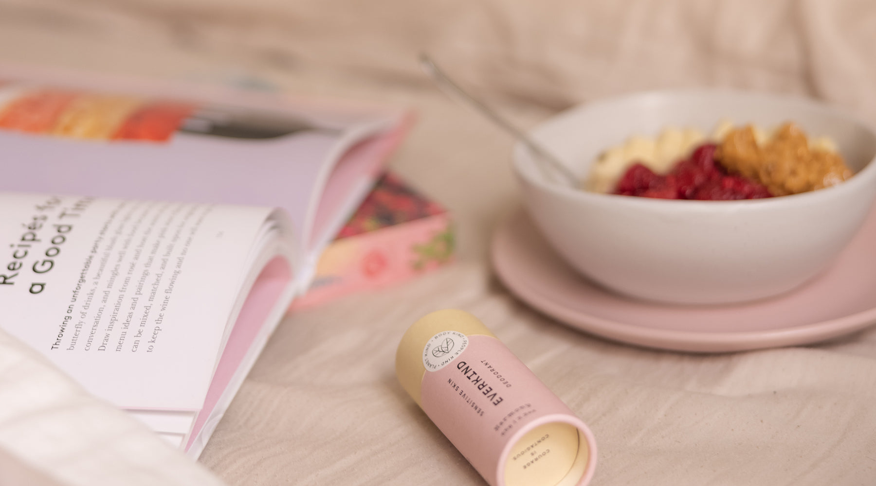 Photo of beautiful breakfast bowl, recipe and Everkind deodorant on a linen covered bed.