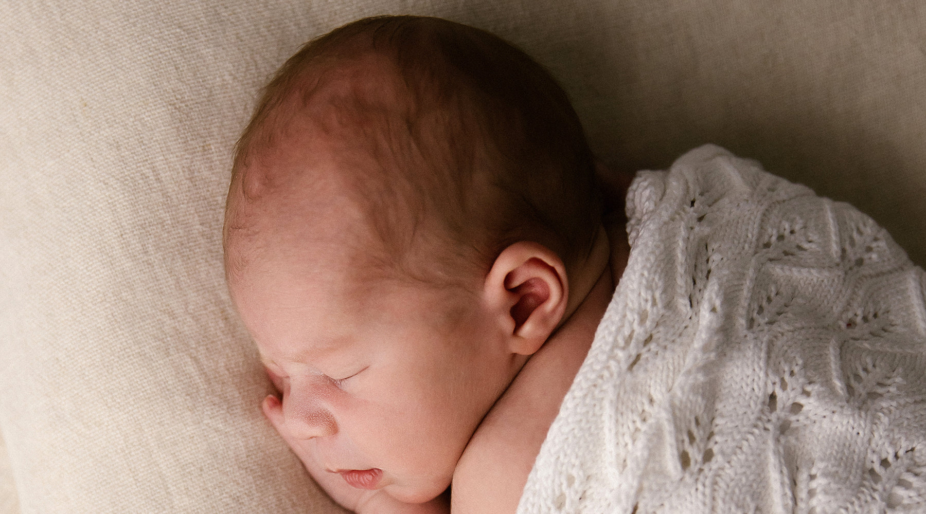 Sleeping baby swaddled in a hand knitted baby blanket.