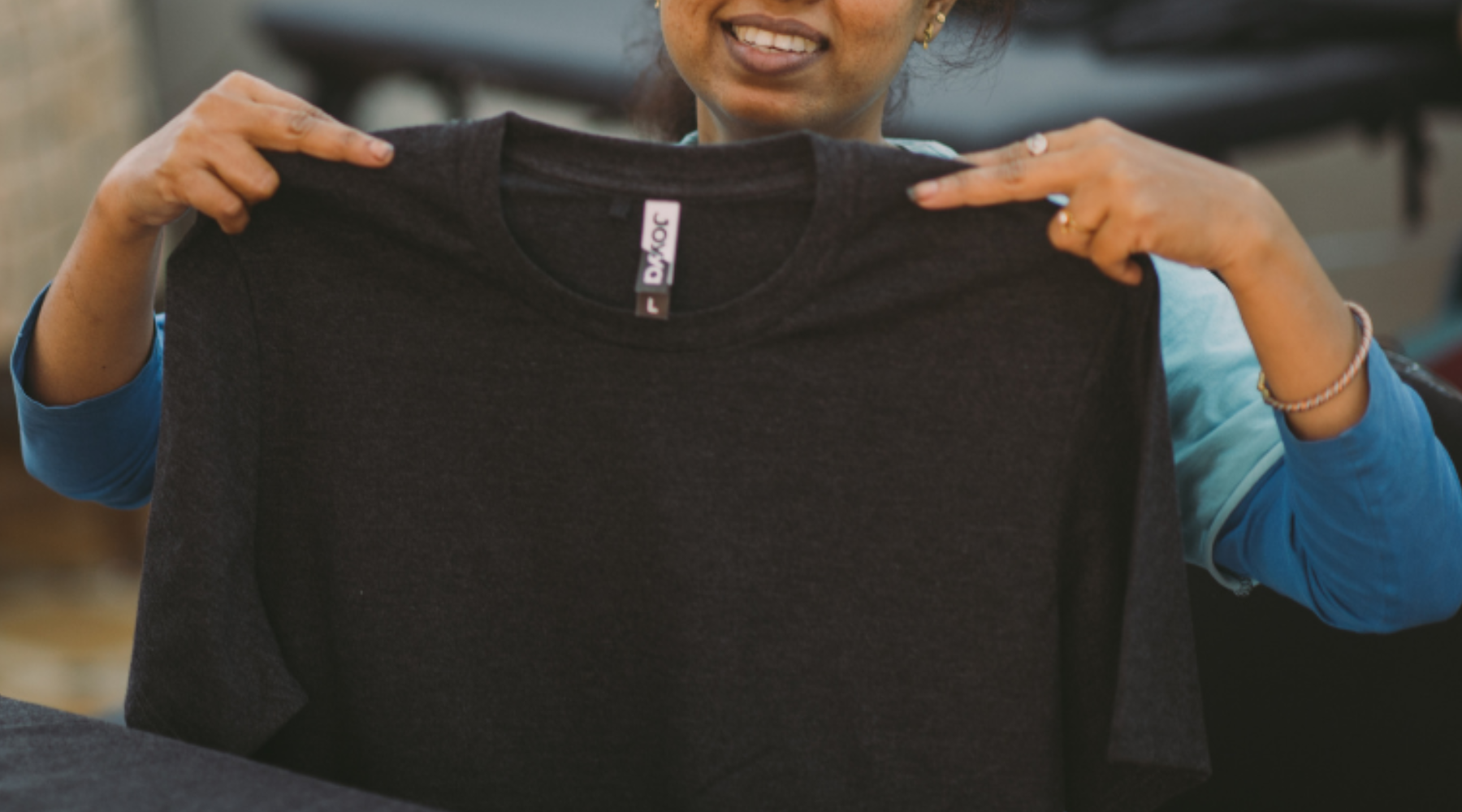 Photo of woman holding black Joyya t-shirt.