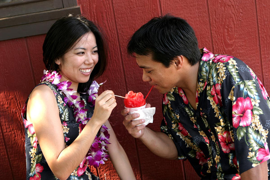 couple in matching Hawaiian shirt and dress share a shave ice