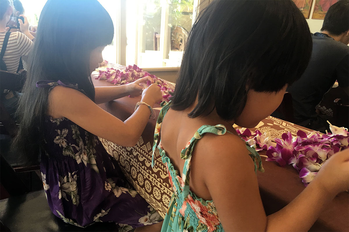 kids learning to make flower leis