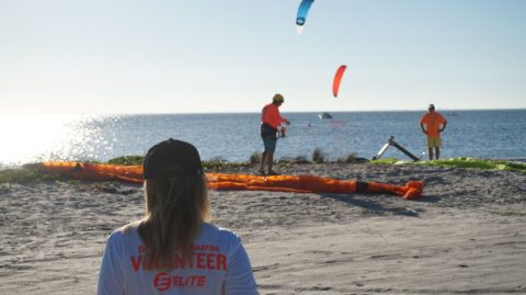 people setting up kites and foils and boards on the beach