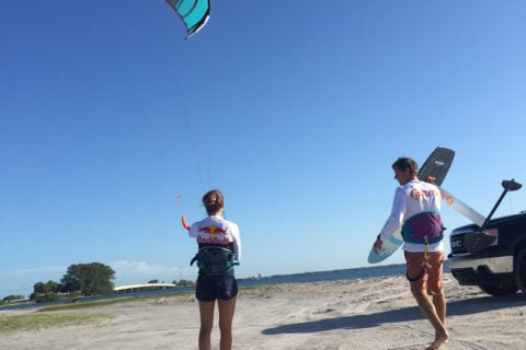 two people on the beach with a kite