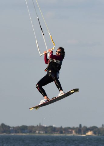 woman on a kiteboard in the air above the water