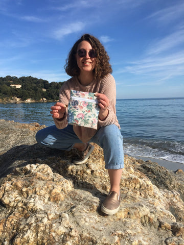 Marielle en voyage dans le sud se tient en équilibre sur une roche un sac à collation fleuri à la main