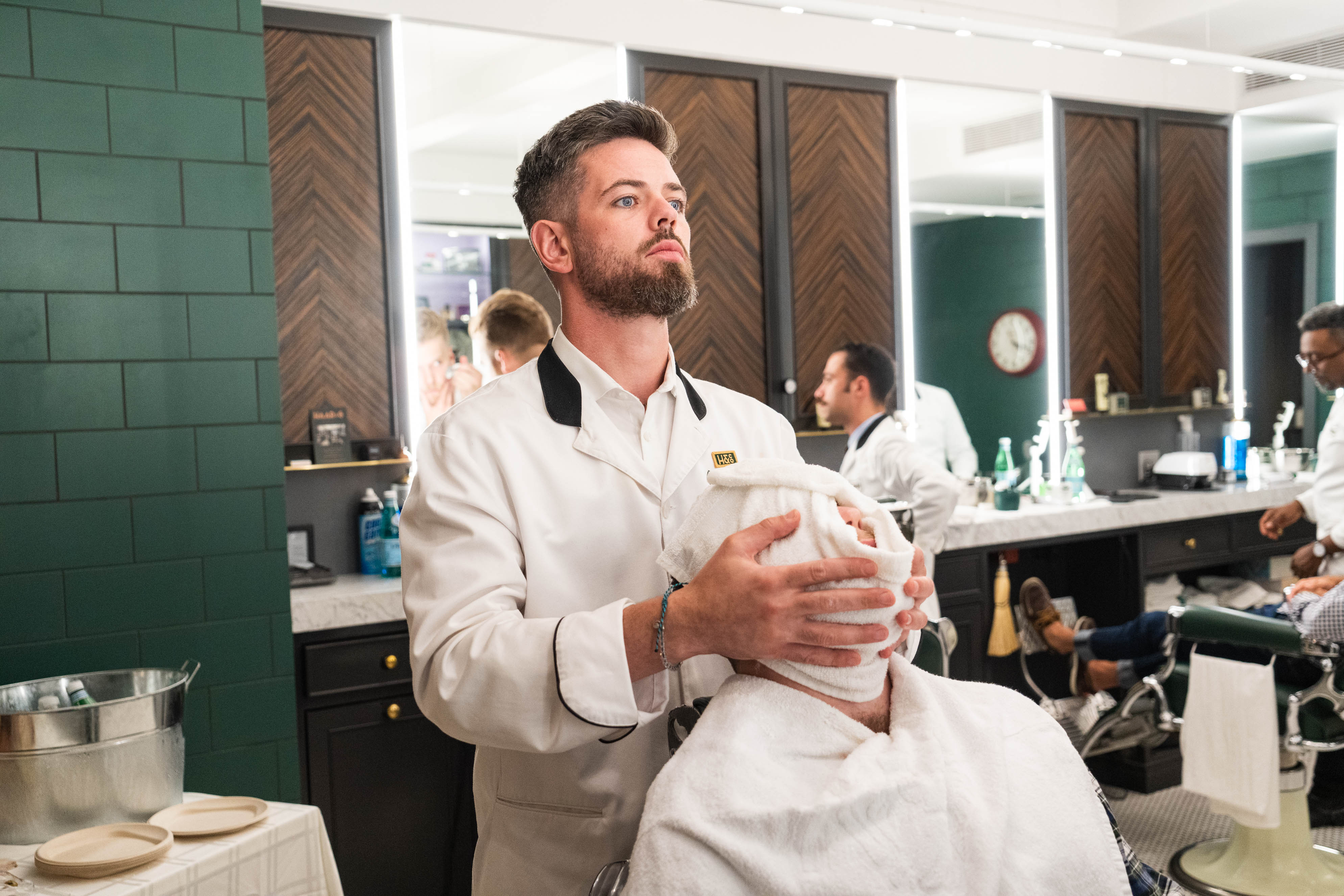 Barber applying a warm towel to a client in the barber chair