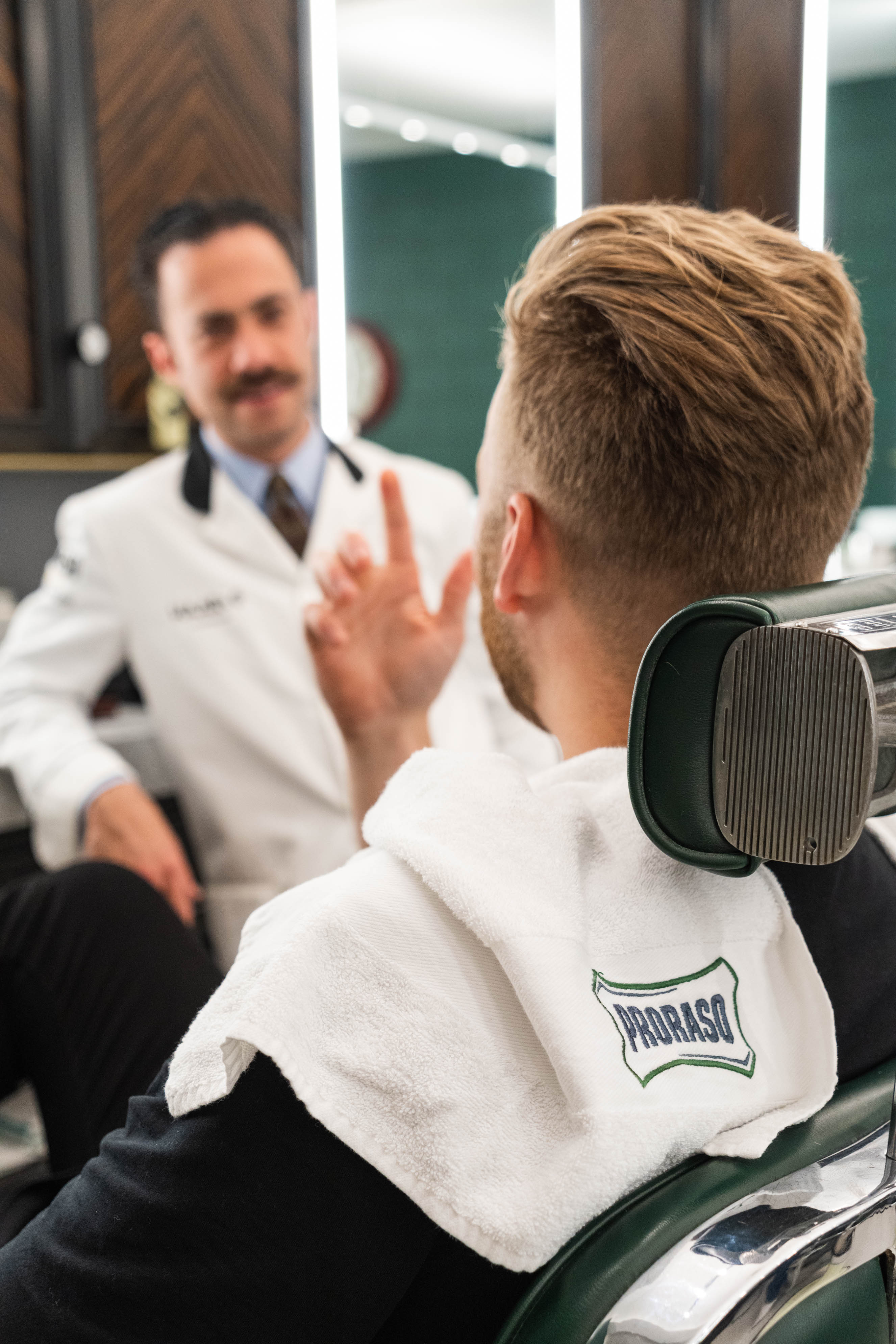 Man getting shaving instruction sitting in a barber chair from Proraso Master Barber Michael Haar.