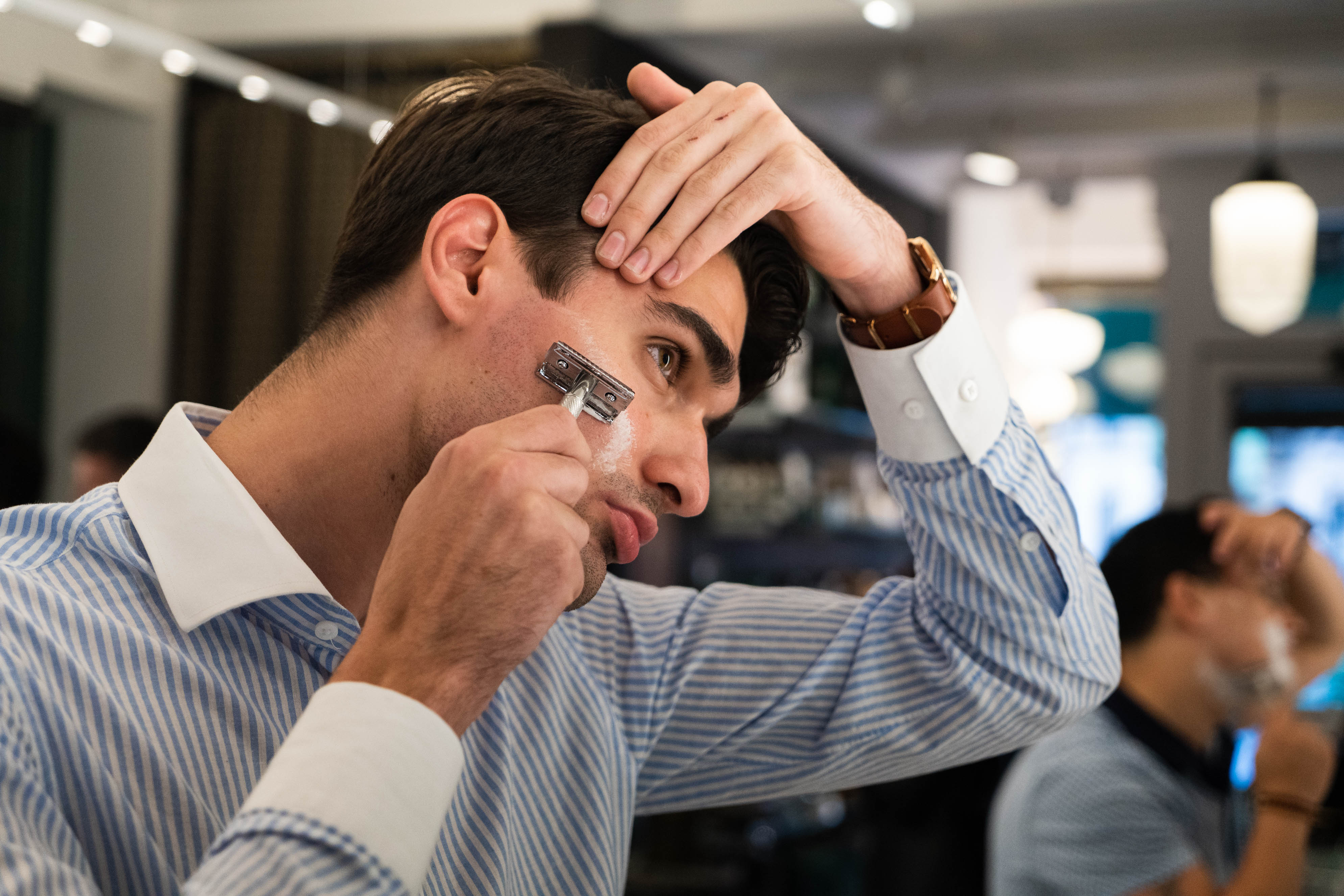 Man pulling his skin tight, shaving with a double edge safety razor