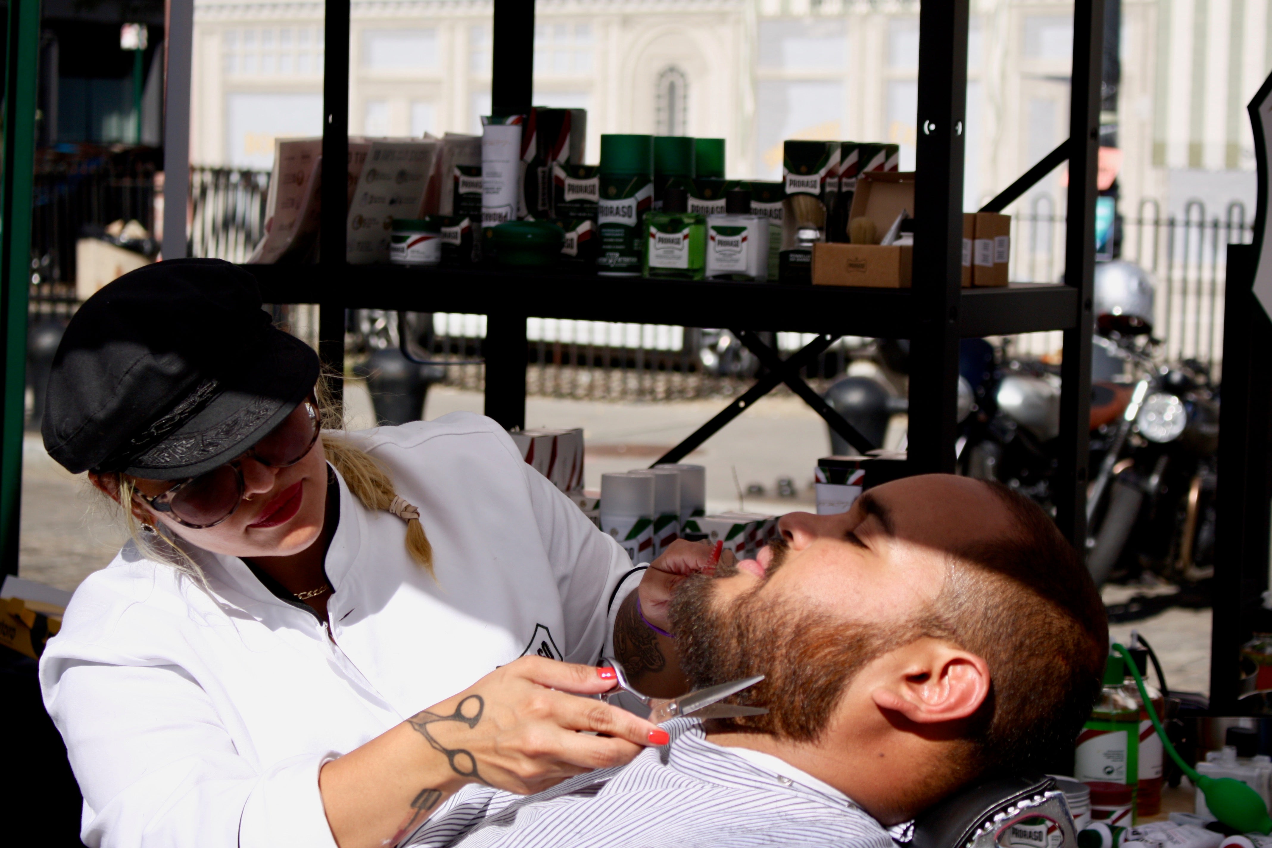 Man in a barber chair getting his beard trimmed with scissors