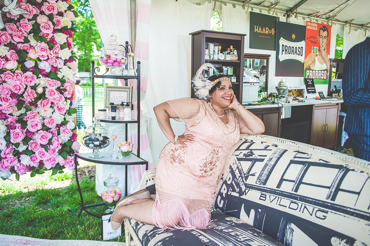 Woman dressed in a pink vintage dressed posing on a vintage style couch