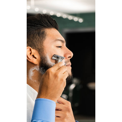 Man shaving the edges of his beard with shaving cream on and double edged safety razor