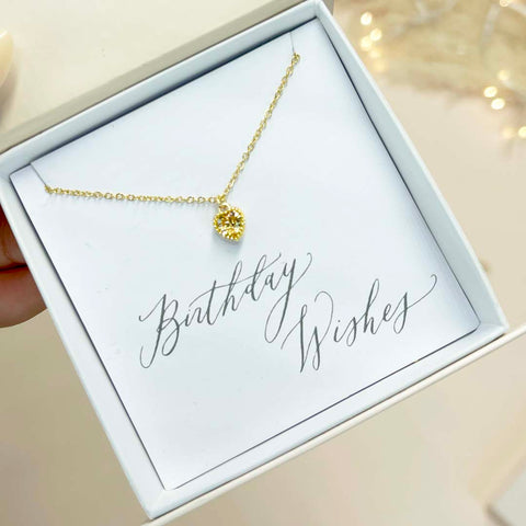 Image shows gold plated heart birthstone necklace in a white gift box with a 'Birthday Wishes' sentiment card