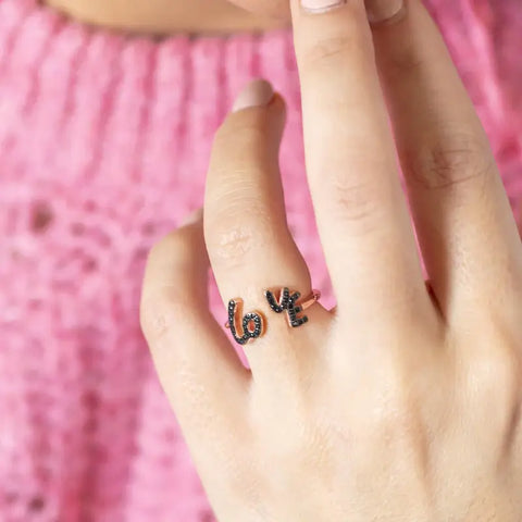 model wears limited edition rose gold 'love' adjustable ring with black crystals