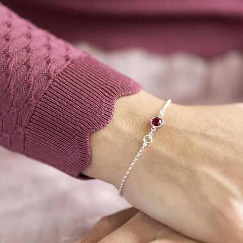 Model wears mother and child birthstone bracelet with red ruby birthstone for mum and green peridot for child on a silver chain