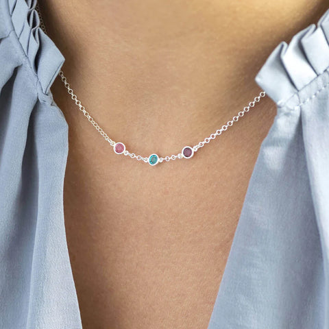 Model wears sterling silver mini birthstone link necklace with three Swarovski Birthstones from left to right: October Rose, December Blue Zircon and February Amethyst