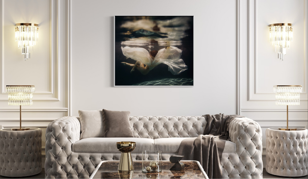 A figural photograph hangs on a white wall above a grey sofa. 