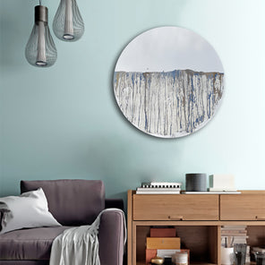 Circular mirror, mounted on wall, with blue and gold mixed media painting on lower half. Displayed in living room above a console with lounge chair to the bottom left.