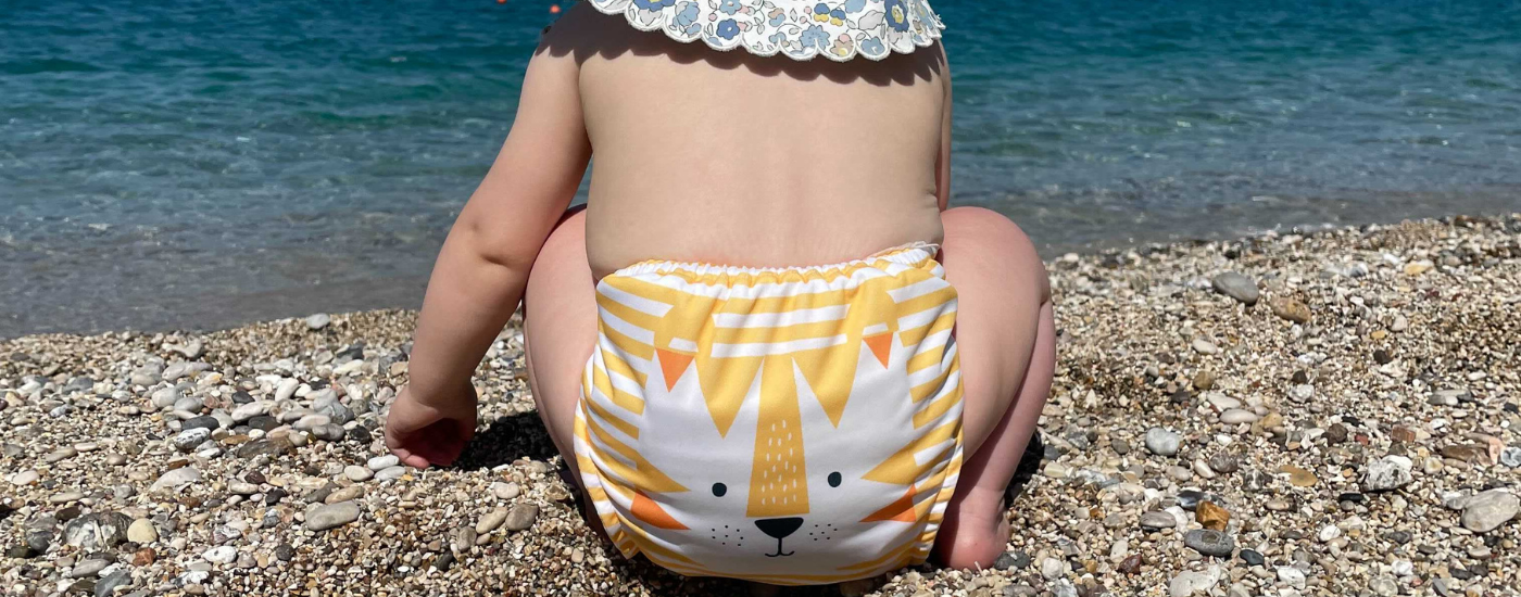 Baby at the beach wearing a reusable nappy