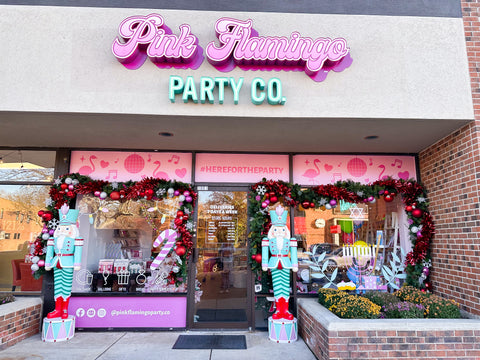 pink flamingo party co, a party store decorated for the holiday season with two nutcrackers outside