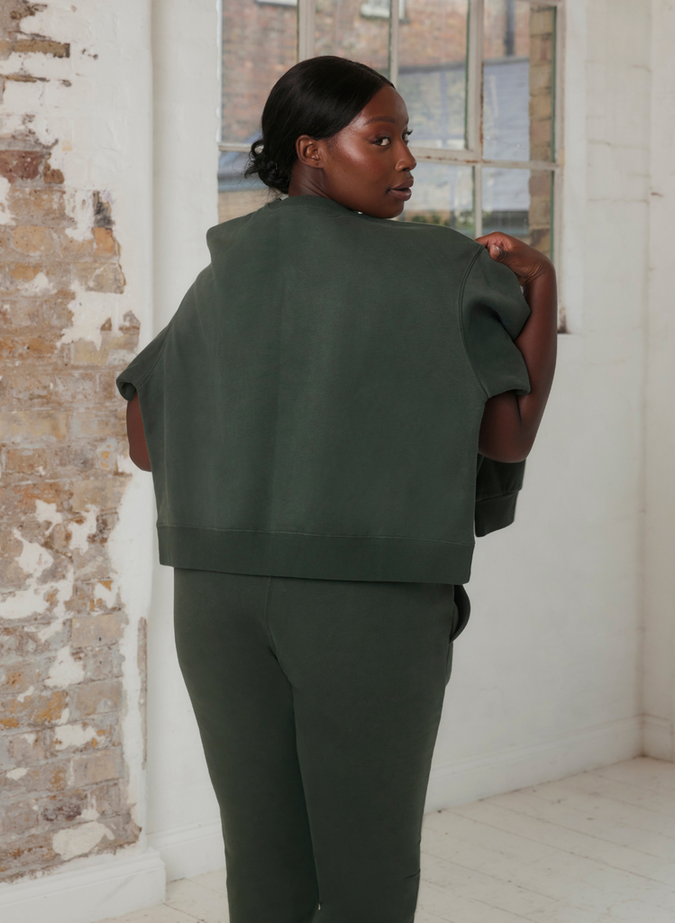 Woman wears the Everyday Jogger Set in Green, with the women's sweatshirt wrapped around her shoulders.