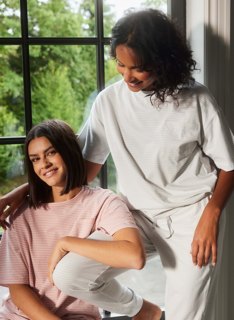 Two women sit infront of a window, smiling and wearing the Brushed Cotton Pyjama Set by LOVALL.