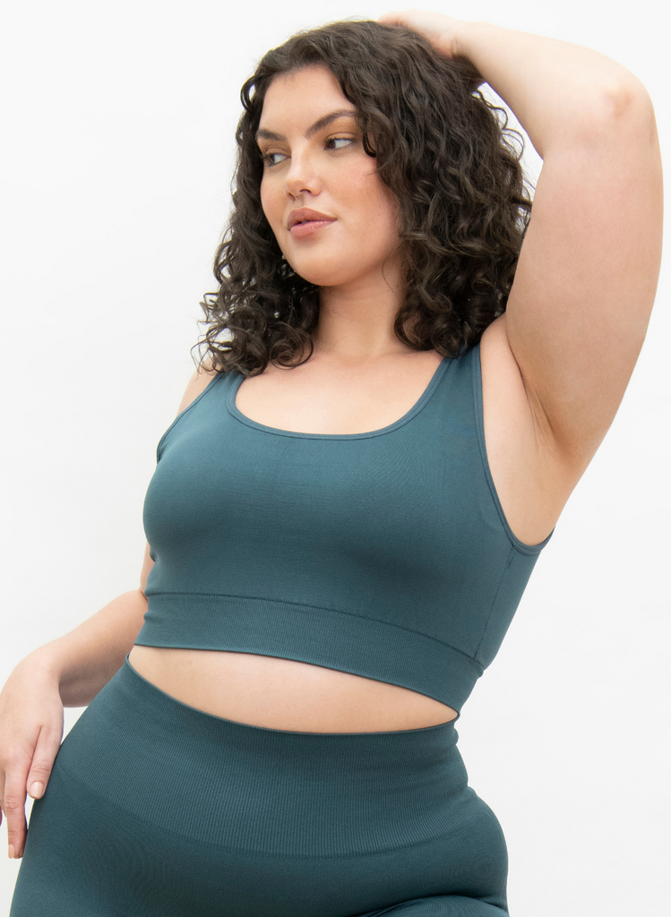 Woman poses with her arm on her head in the Seamless Set in Teal.