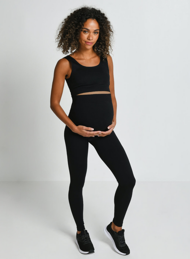 Pregnant woman stood on white background wearing the Black Seamless Maternity Set.