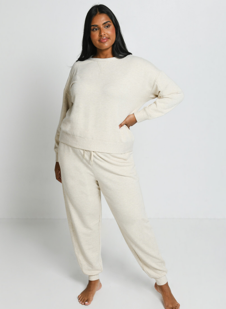 Woman stands against white backdrop wearing the Vanilla Marl Luxe Jogger Set in Curve.