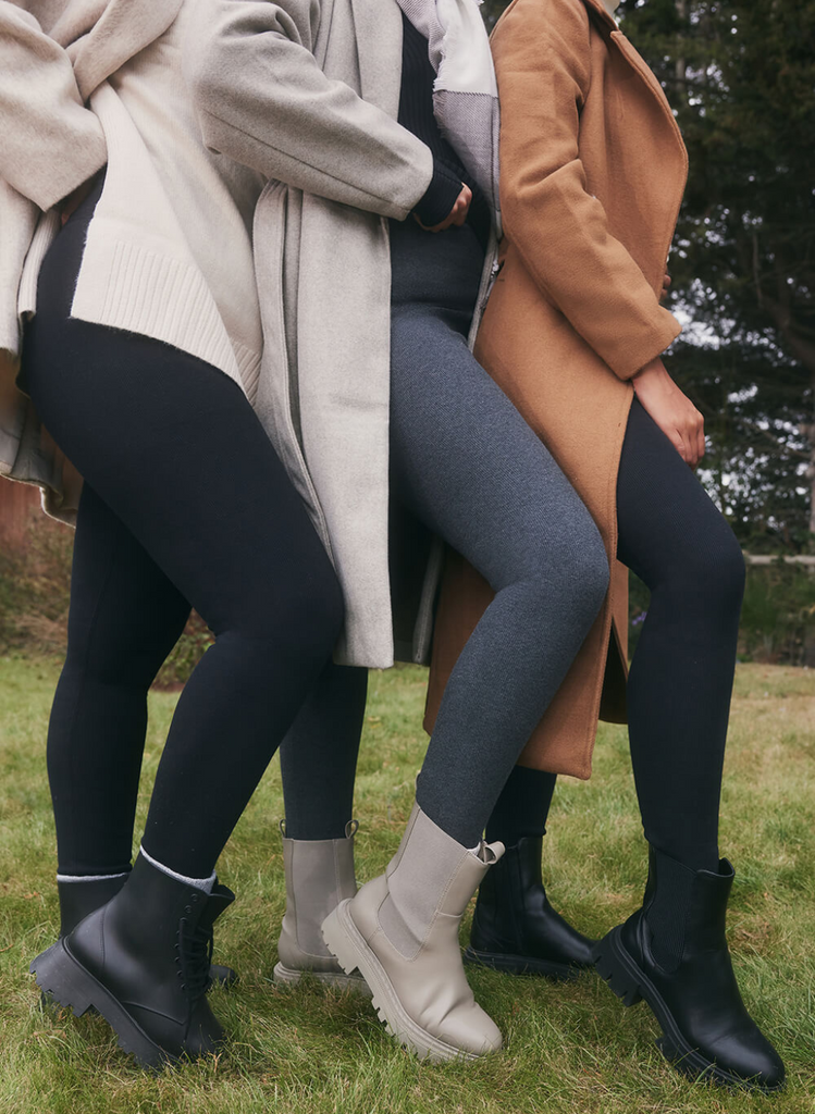 Three models, just a shot of their legs wearing the Extreme Fleece Lined Leggings by LOVALL. The woman in the middle is pregnant, and all three women are wrapped in winter layers and are stood outdoors.