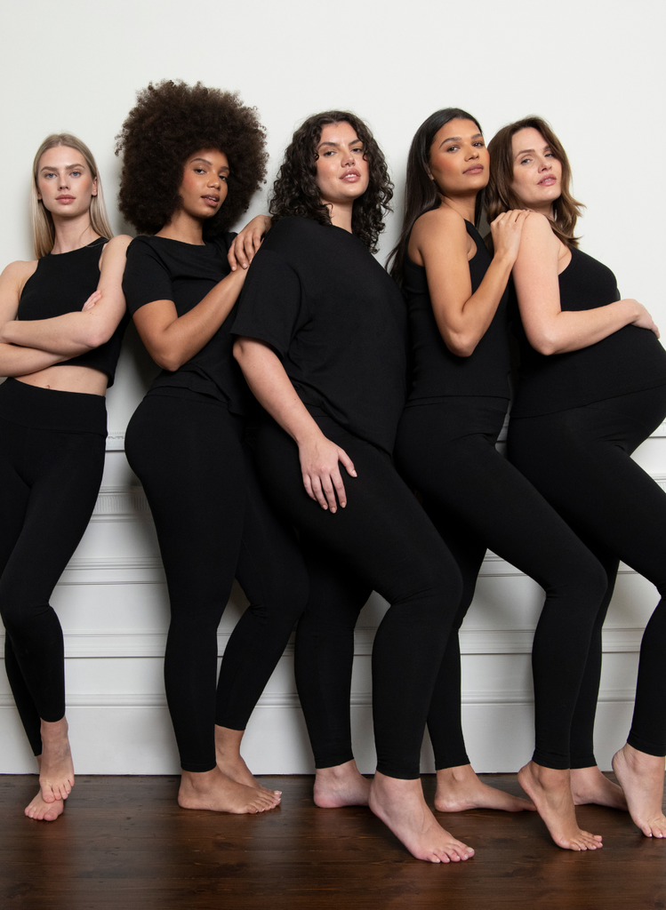 LOVALL models of all different sizes, and a pregnant model, pose together in the Everyday High Waisted Leggings and various LOVALL Black Tops.