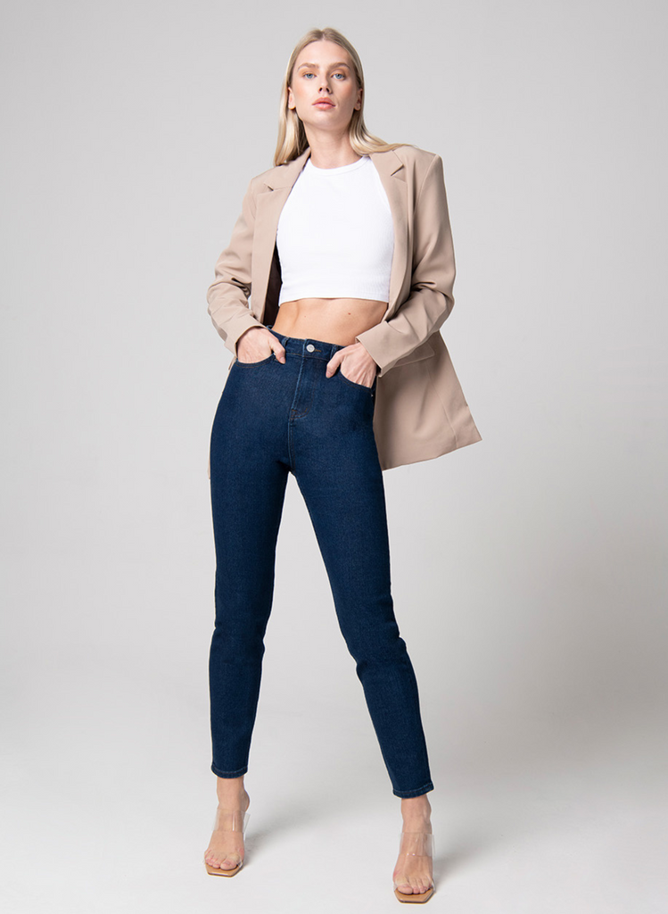 Model wears the dark blue Mom Jeans with white crop top, beige blazer, and heels.