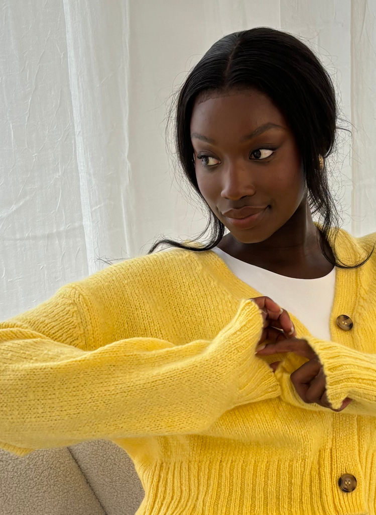Model wears a yellow cardigan and white tank top.