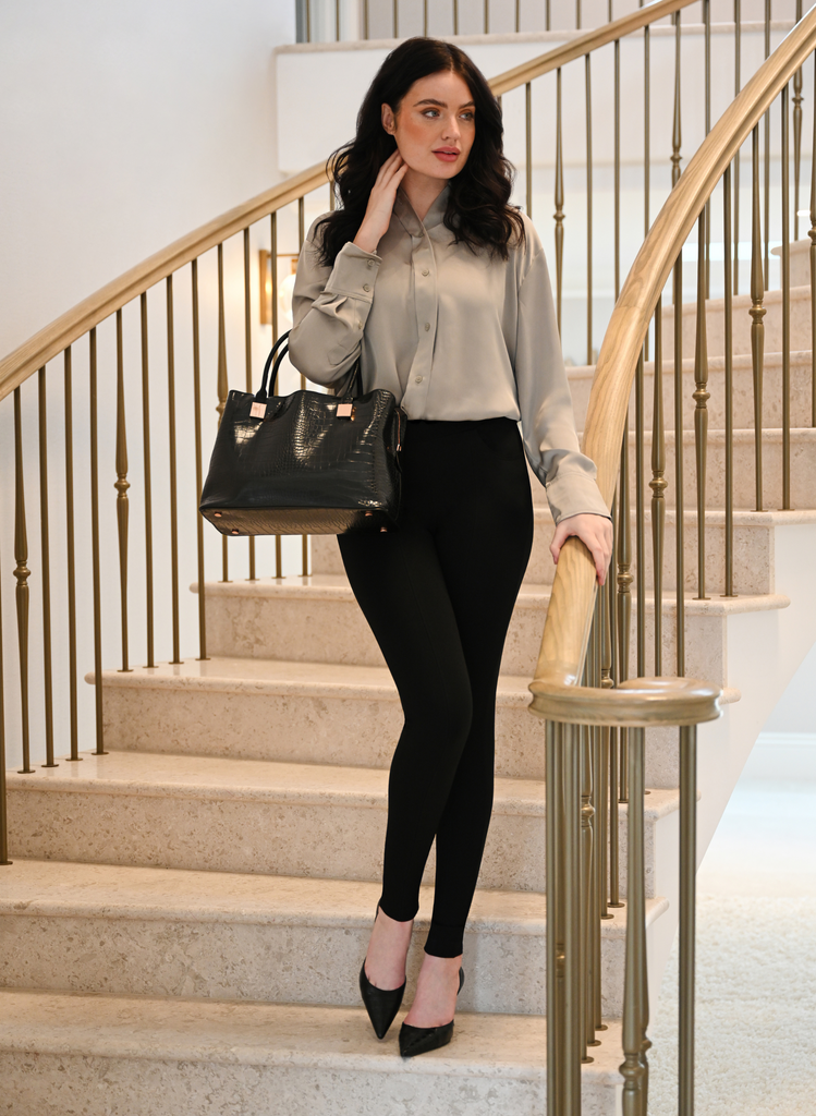 Woman stands on the stairs in Black Treggings, a Beige Shirt, and Black court heels.