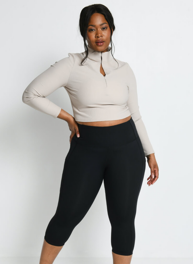 Model wears Cropped Black Gym Leggings with a long-sleeved, cropped quarter zip top.