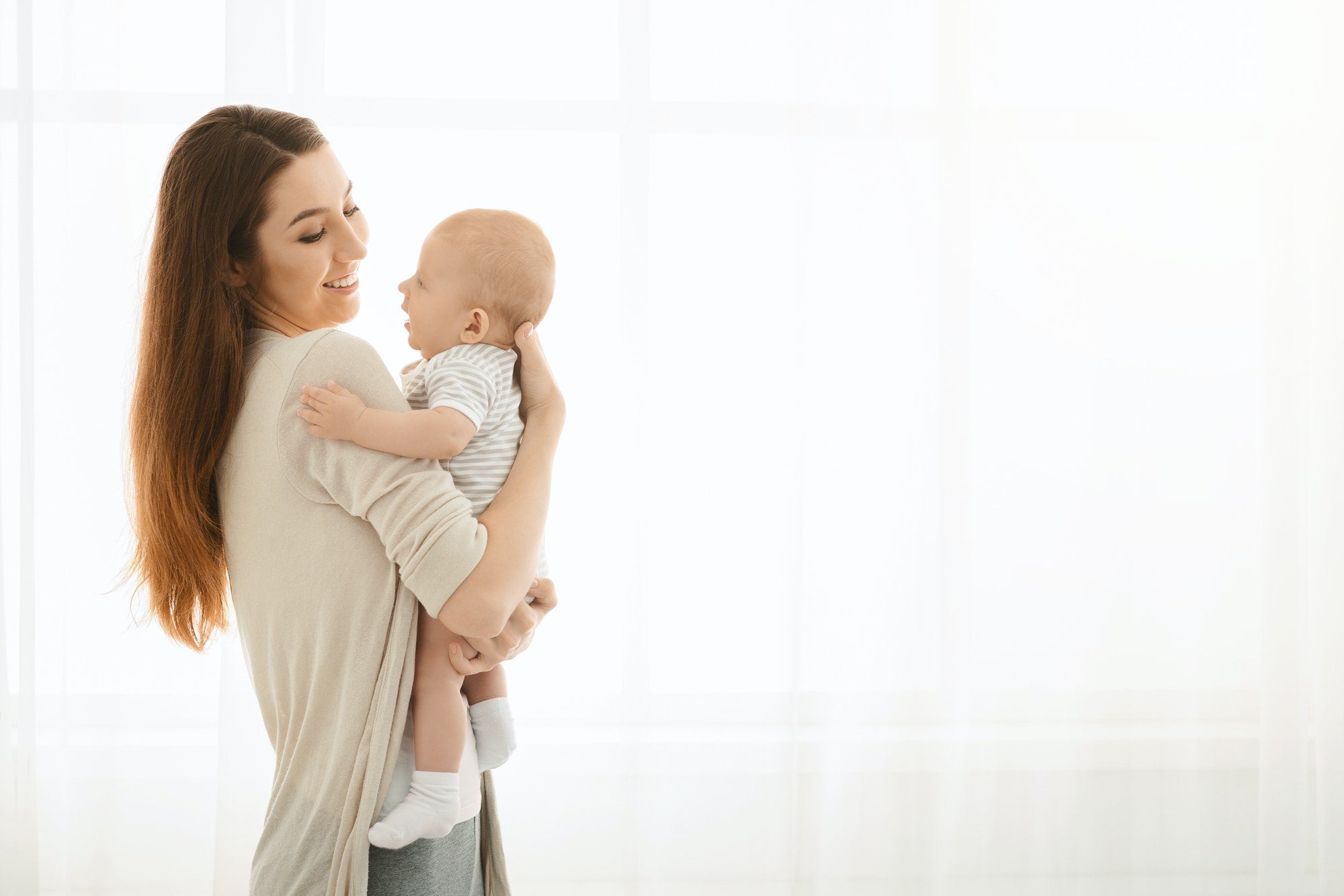 Happy mother enjoying time with her cute baby at home