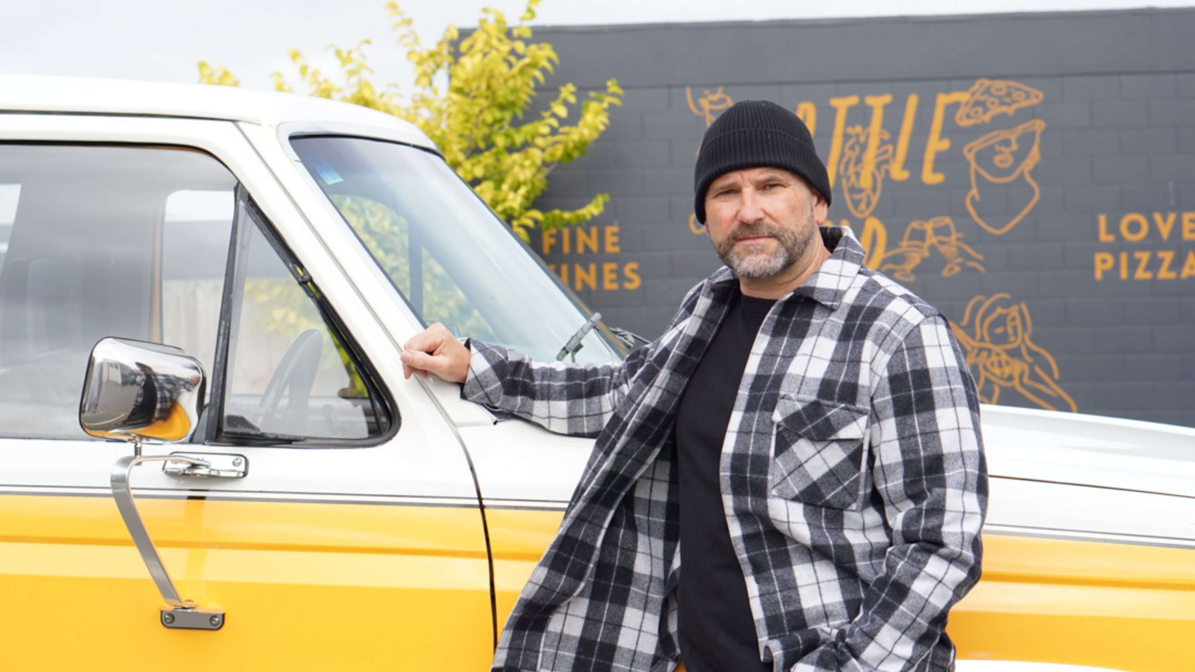 Ed Burak, standing next to his car wearing a check Shacket