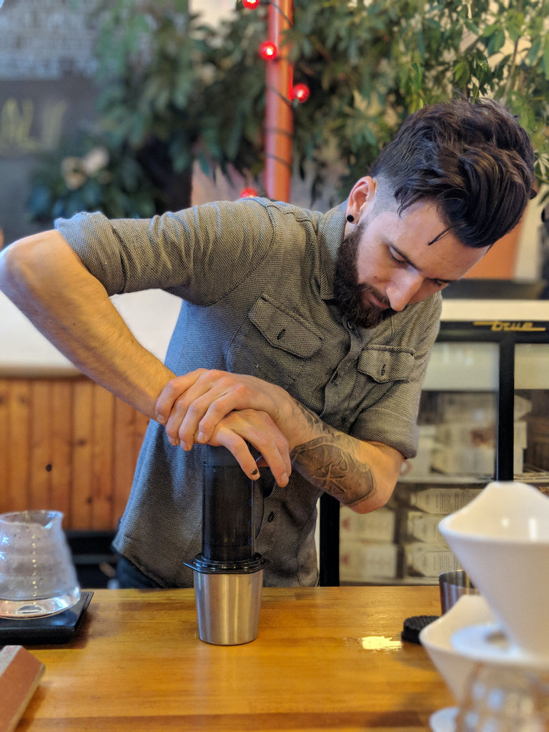 A barista making a coffee using an AeroPress