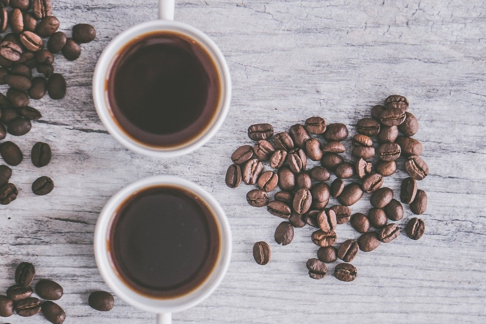 coffee cups next to coffee beans