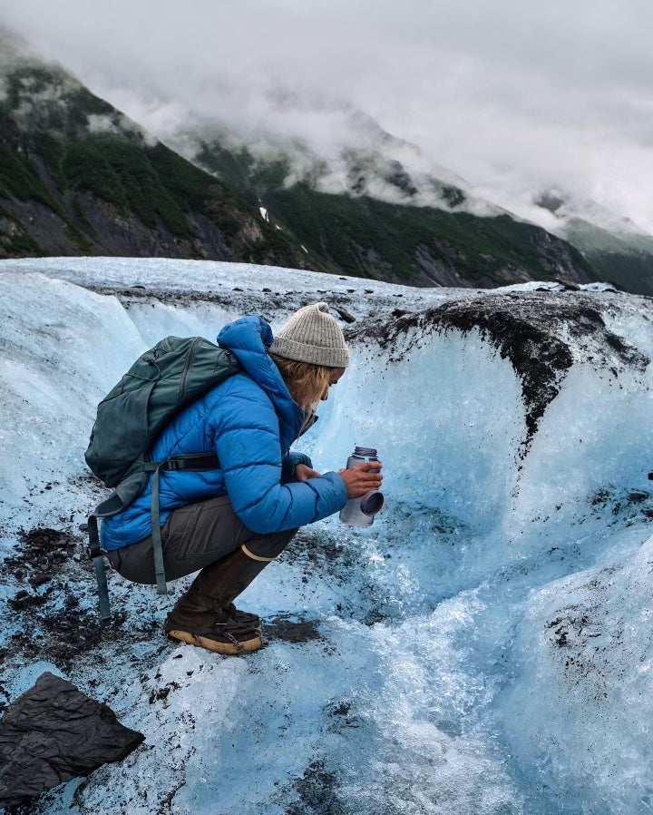 A women hiking a glacier in alaska after kayaking to the glacier with her husband.